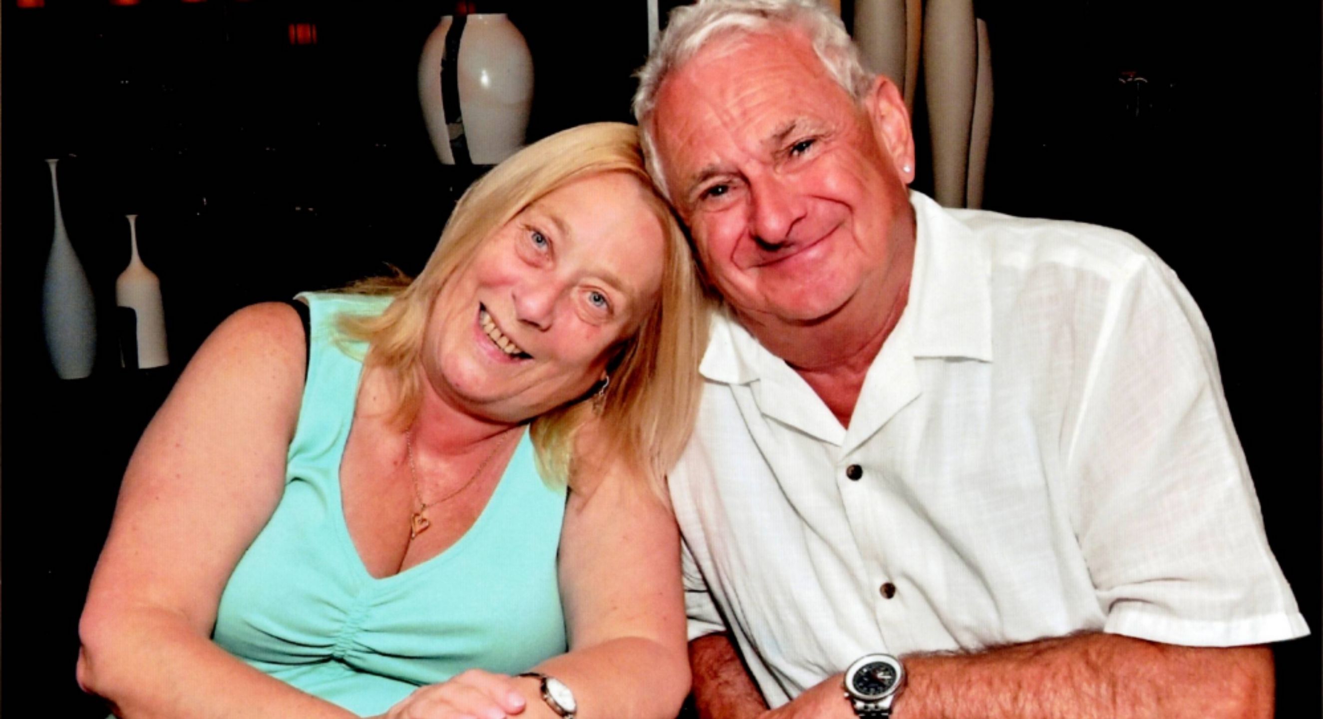 An adult couple smiling and leaning close together