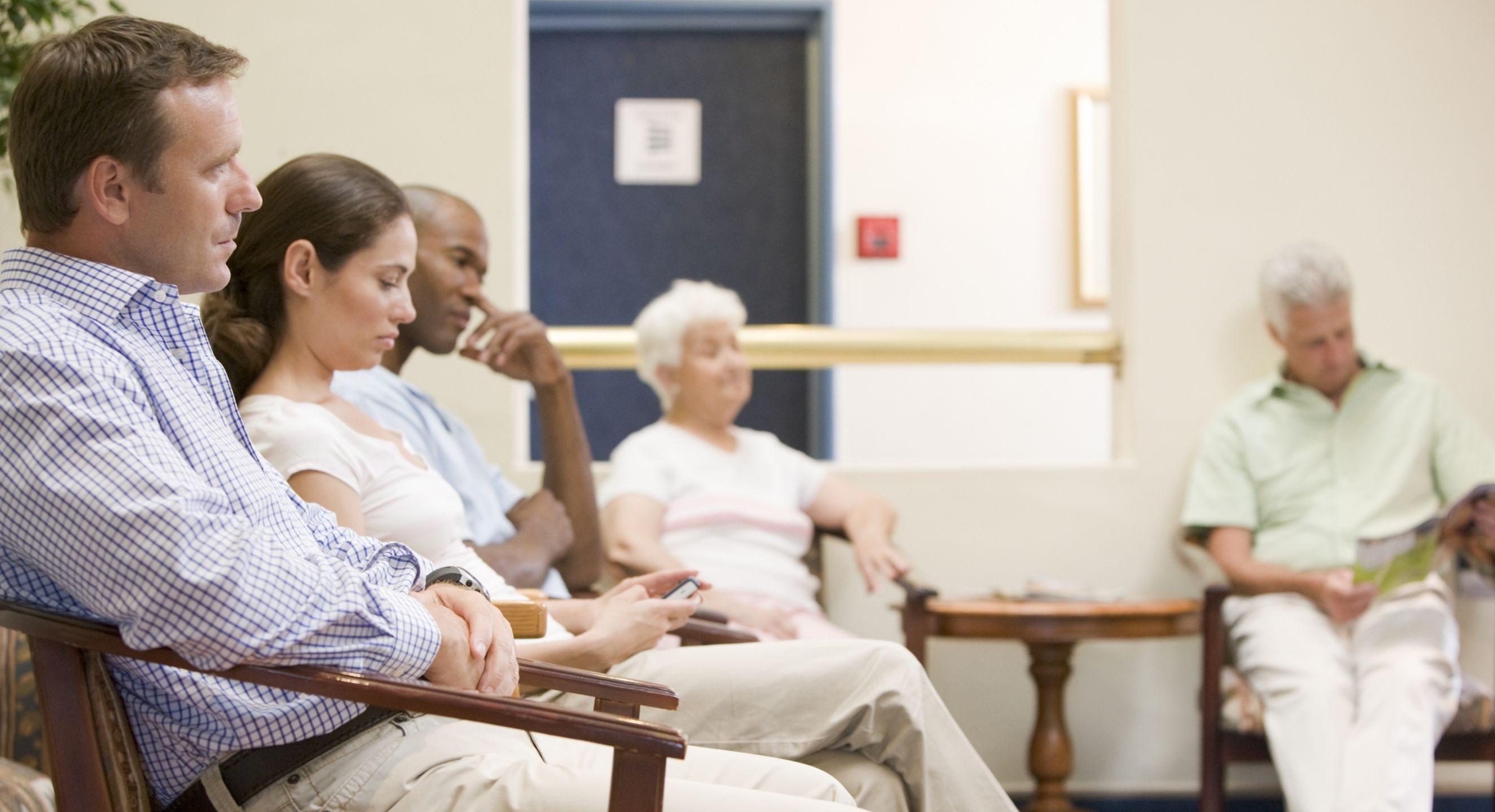 People waiting inside doctor's surgery waiting room