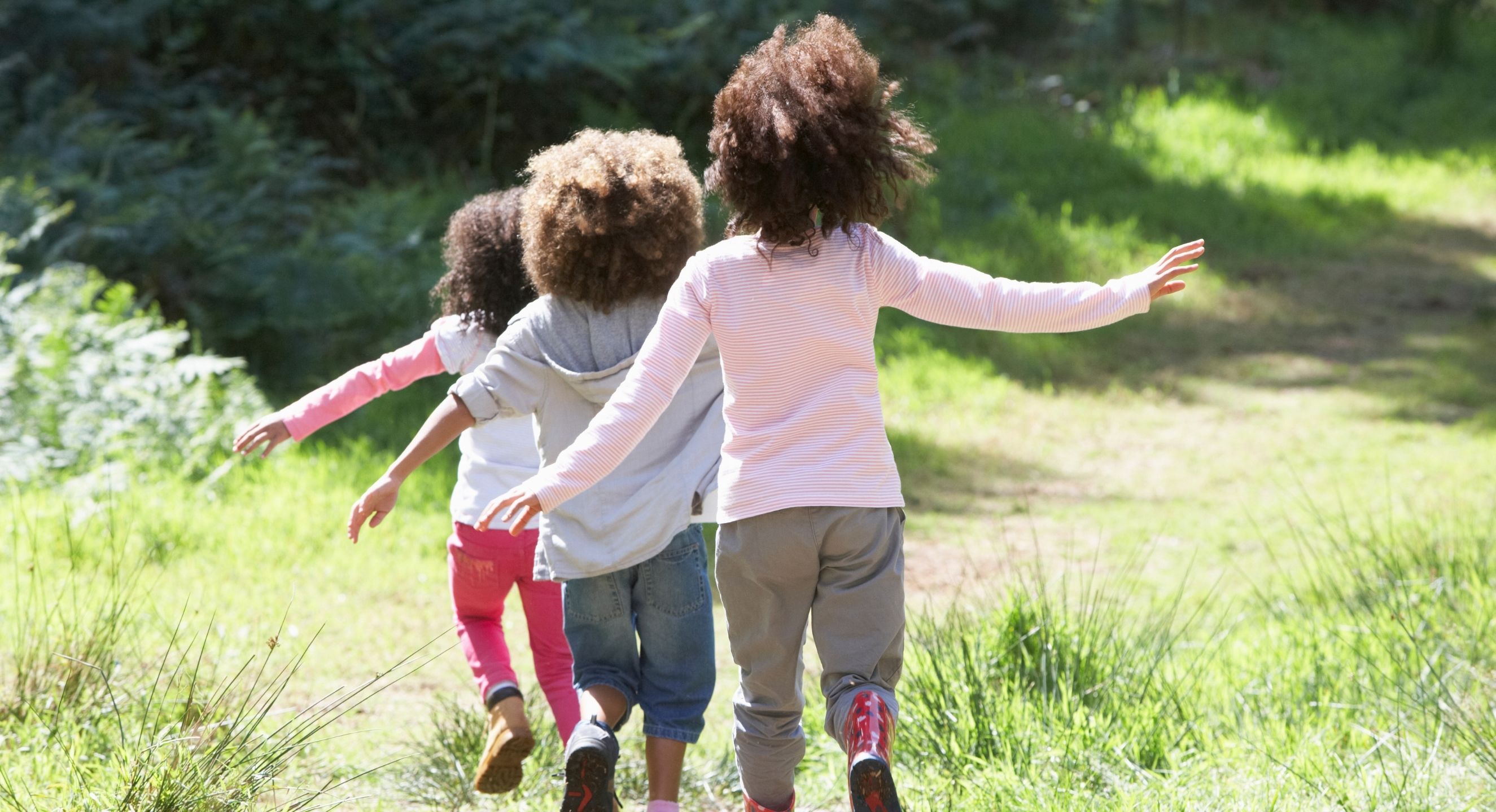 Three children playing outside on grass