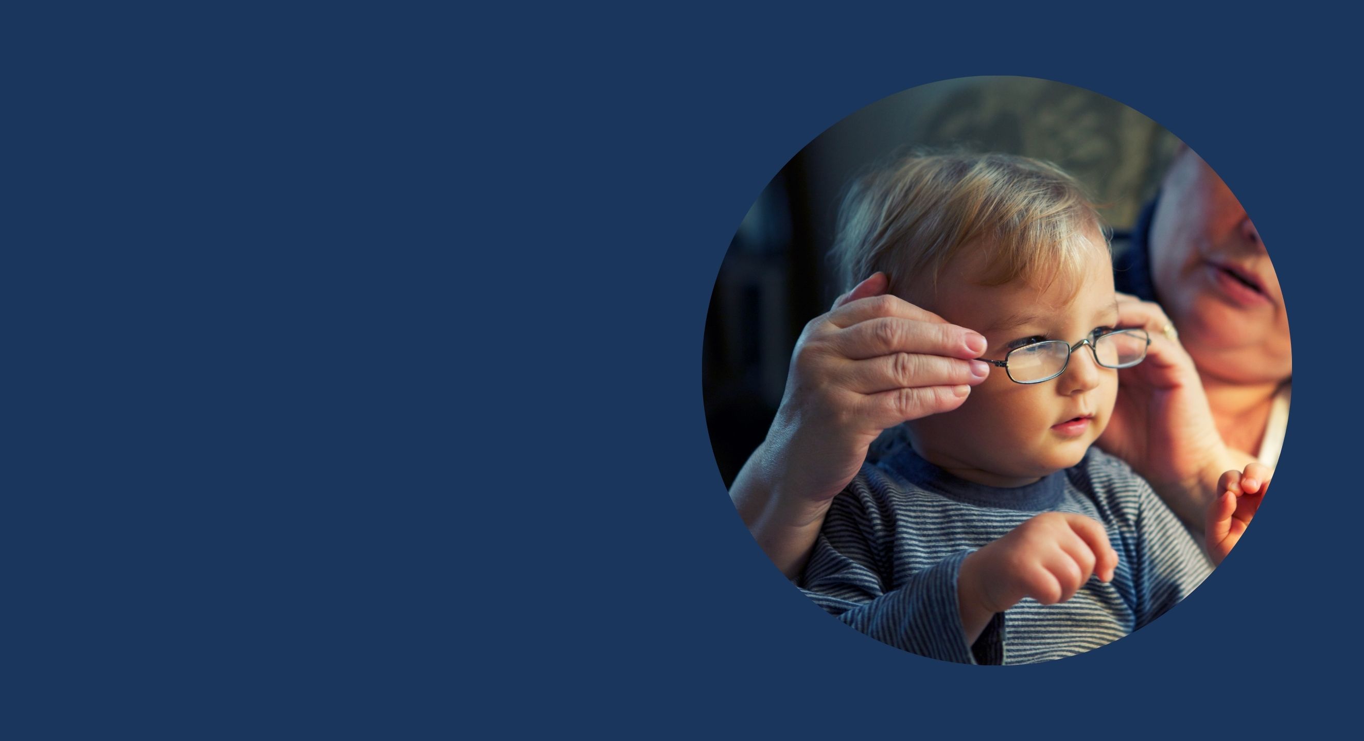 Young child having glasses put on by adult