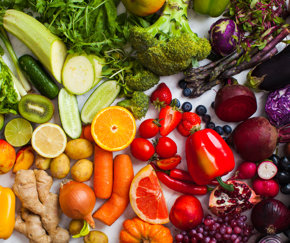 a close-up image of various colourful fruits and vegetables, including peppers, carrots, tomatoes and grapes