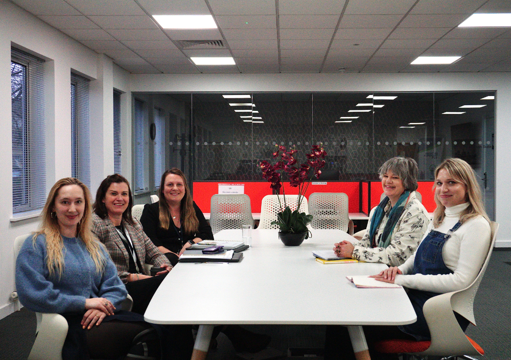 5 members of the Sight Research UK team sat at conference table and smiling