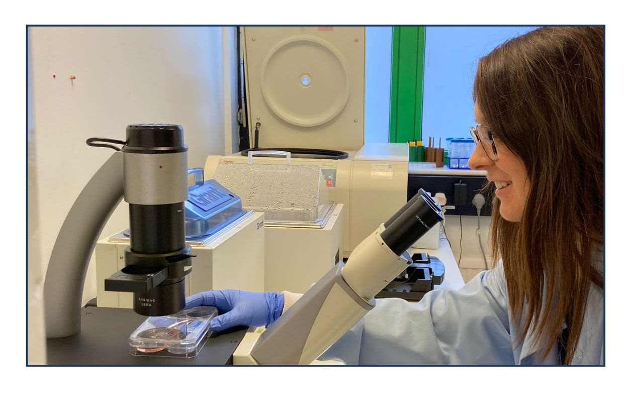 Evangeline Foster looking through a microscope at lab samples